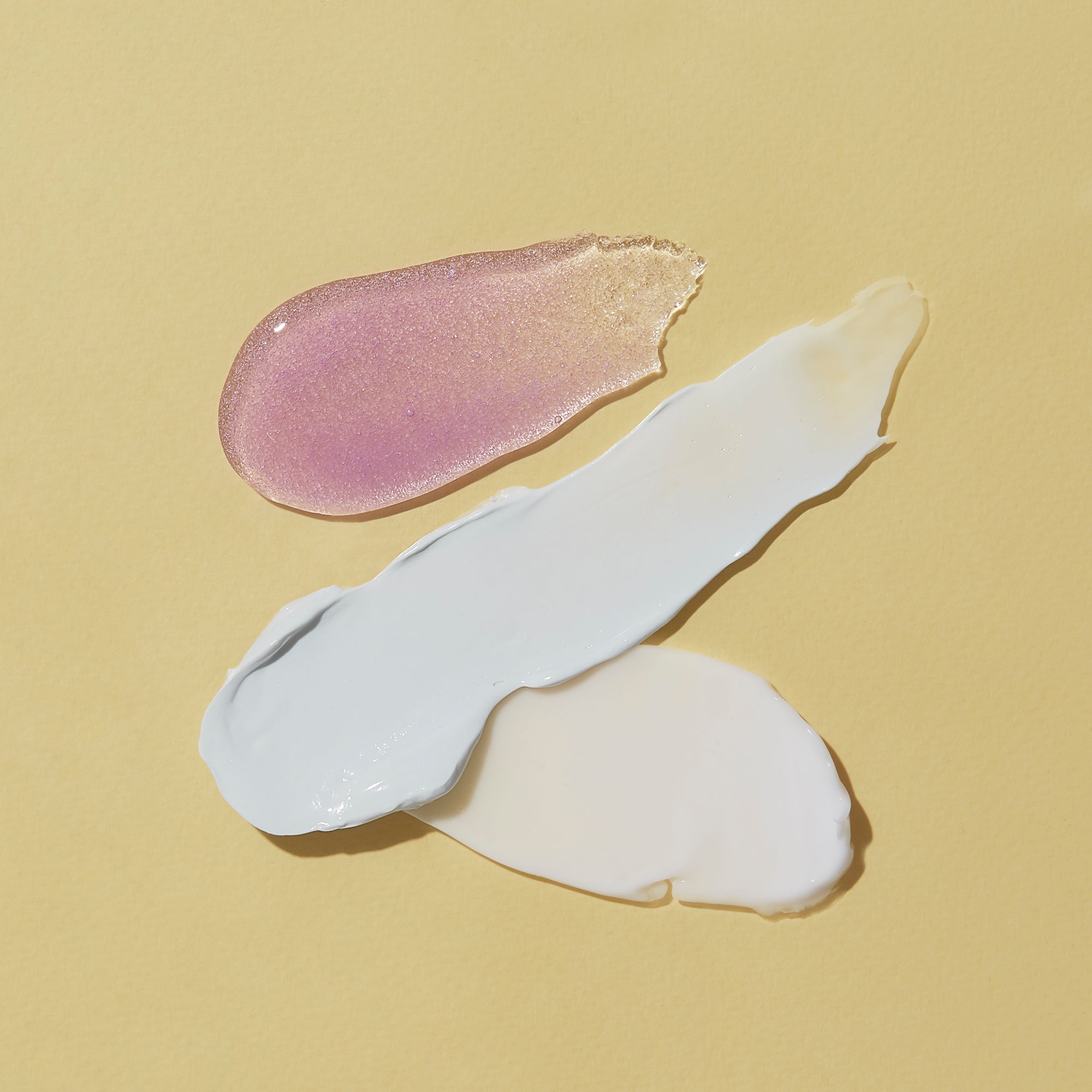 Three swatches of different colored creams on a beige background